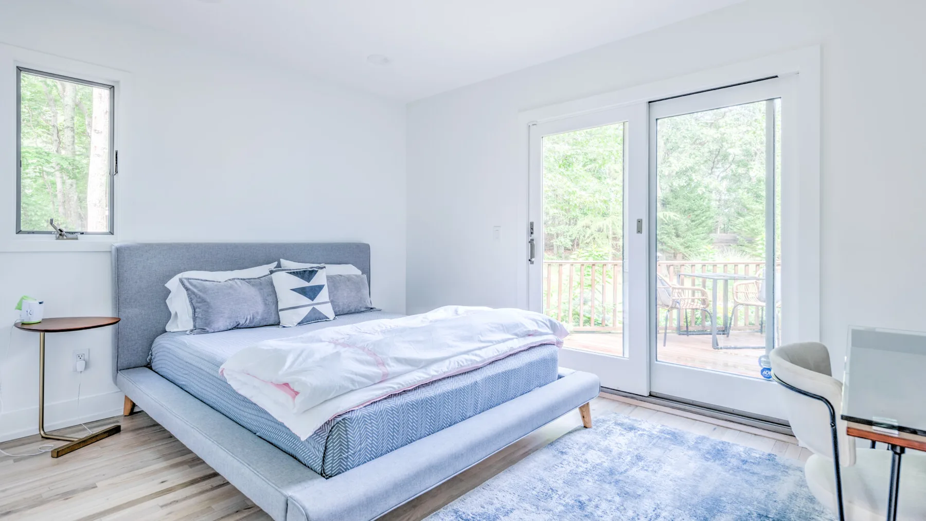 Un dormitorio luminoso con una cama junto a puertas de vidrio que dan a un balcón.