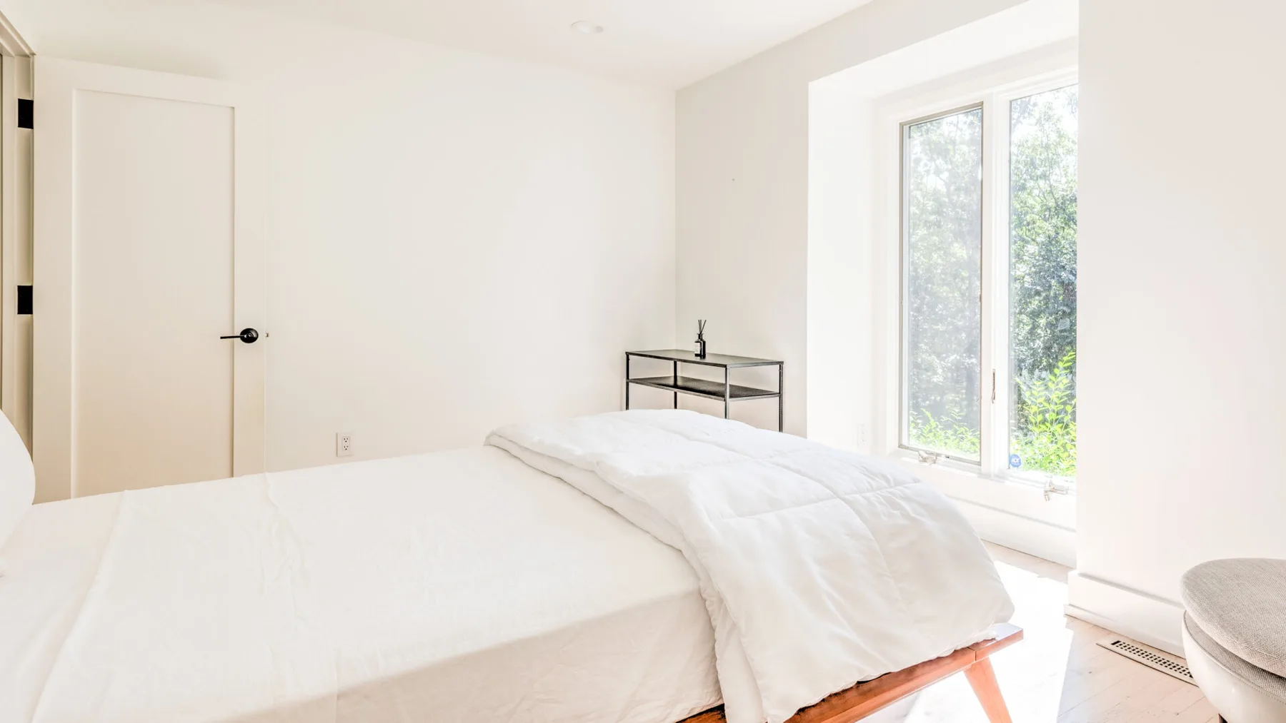 Un dormitorio luminoso con una cama junto a una ventana grande.