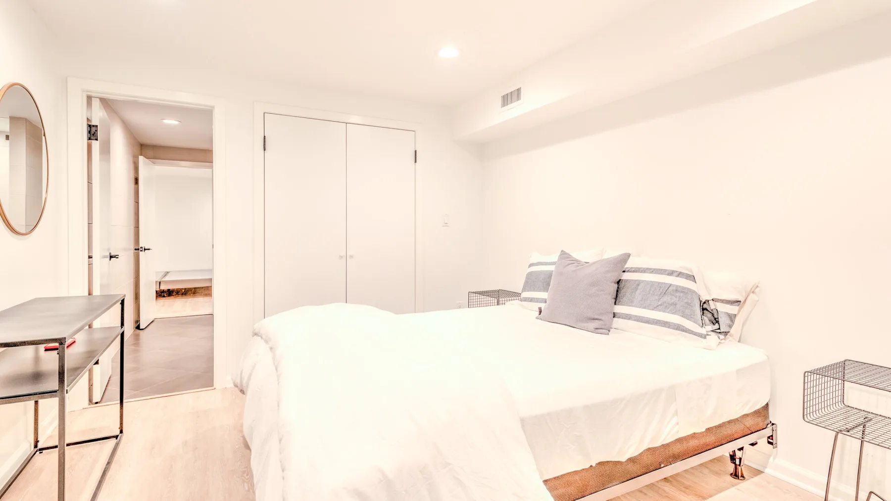 Un dormitorio luminoso con una cama tendida y una mesita de noche.