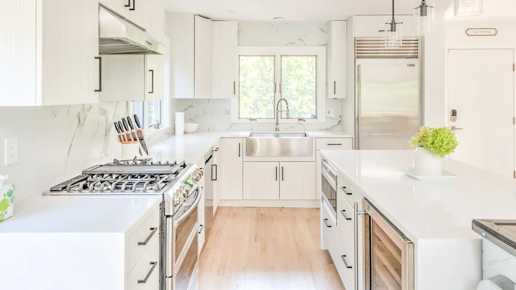 Una cocina luminosa con gabinetes blancos, una isla central y electrodomésticos de acero inoxidable.