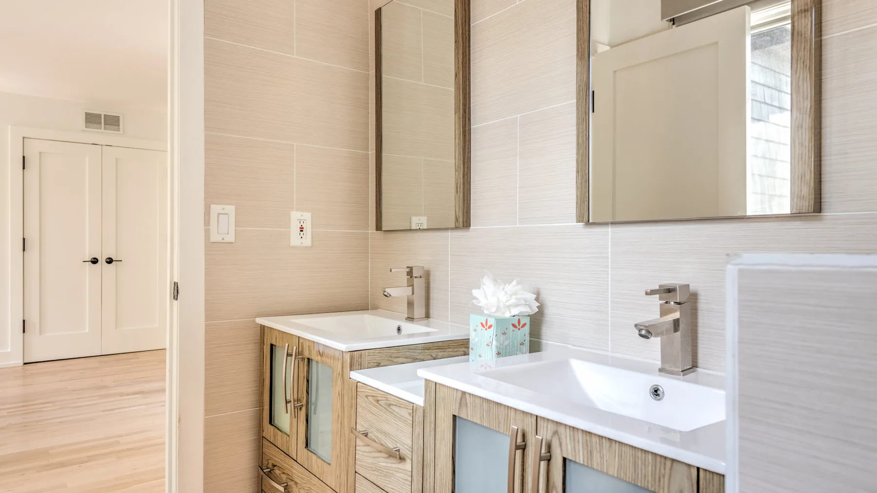 Un baño luminoso con dos lavabos y armarios con espejo.