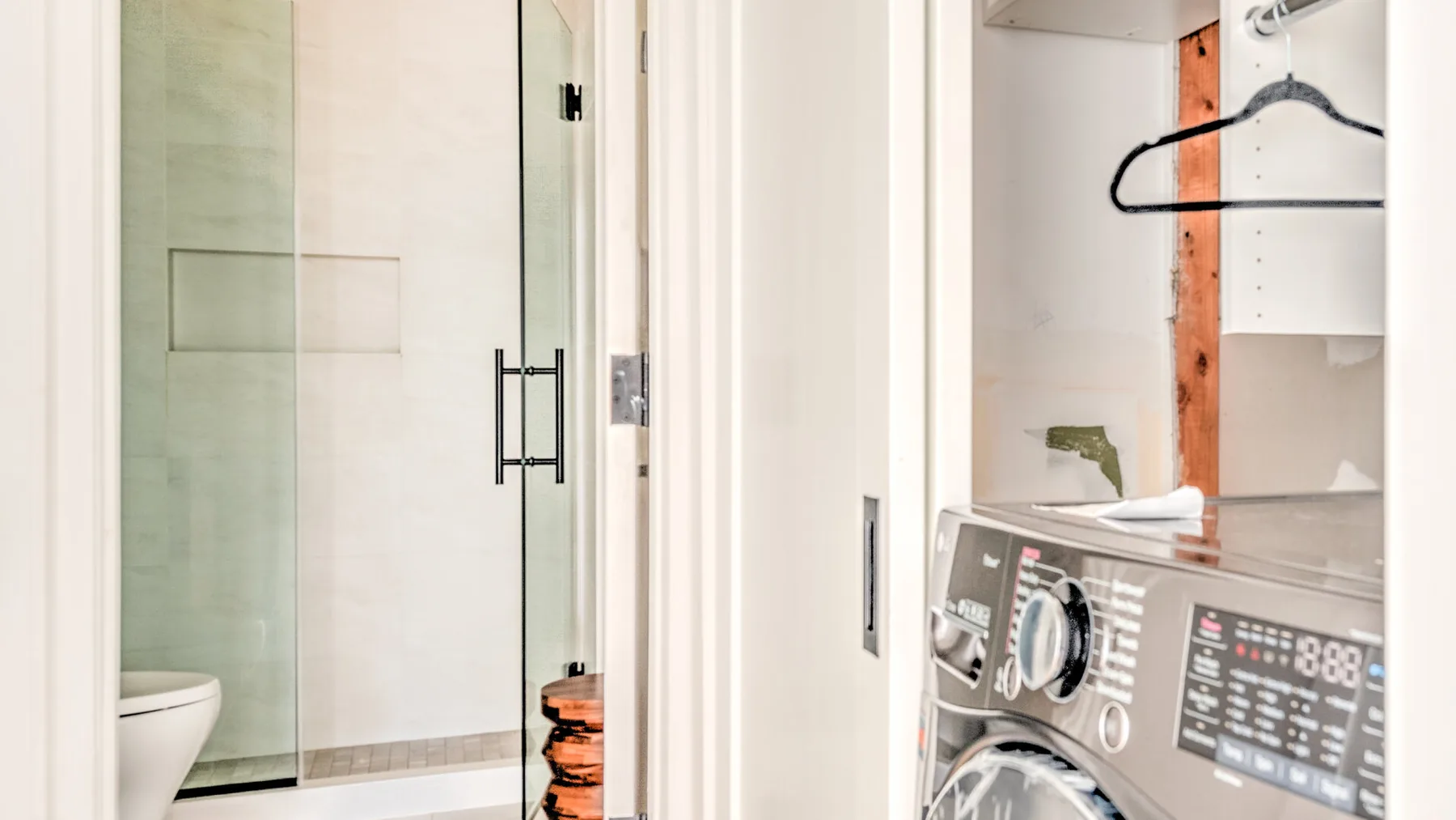 Un baño con ducha de vidrio, inodoro y electrodomésticos de lavandería.
