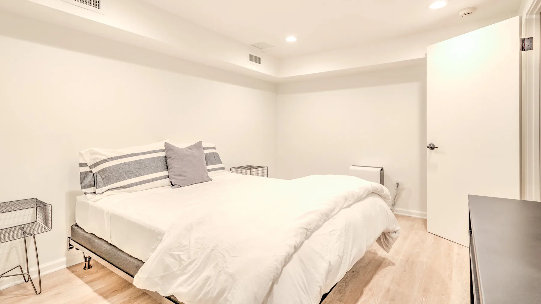 Un dormitorio luminoso con una cama bien tendida y una puerta abierta.