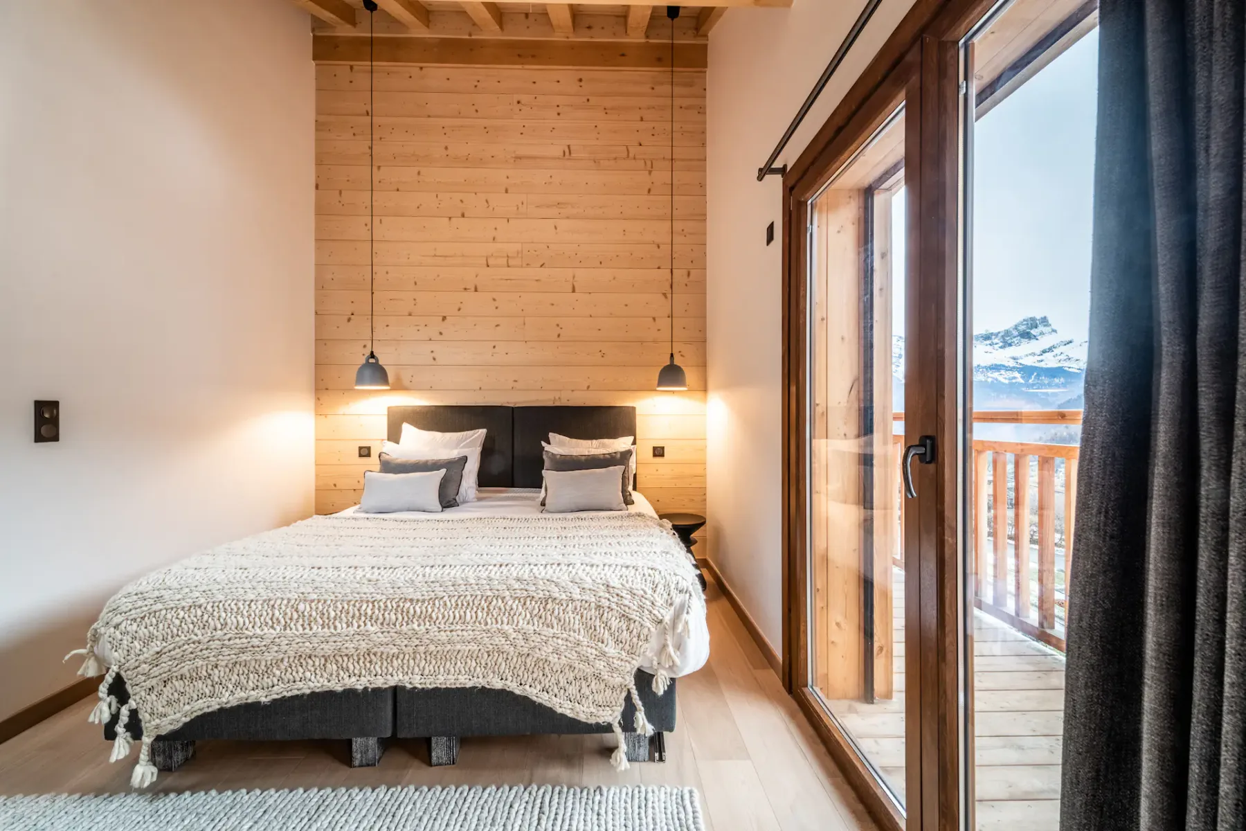 A bedroom with a double bed, bedside lights, and glass doors opening onto a balcony.