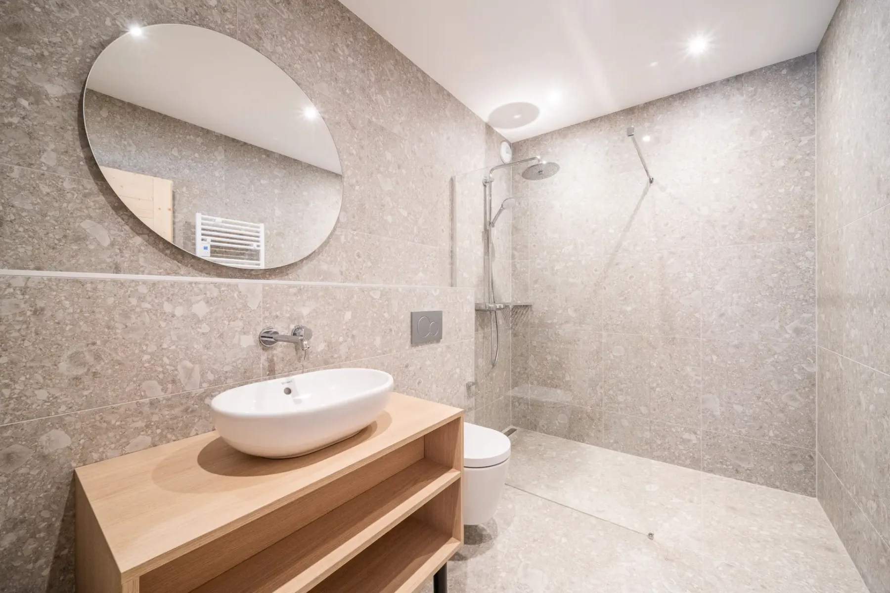 A bathroom with a round mirror above a sink and a shower.