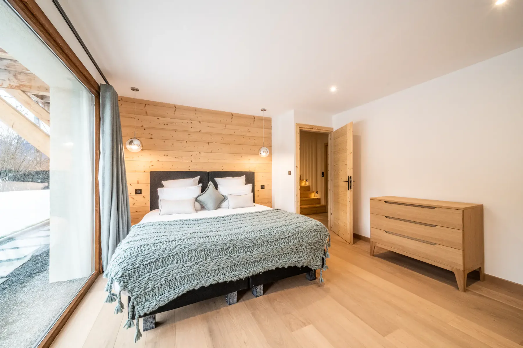 A bedroom with a bed beside a large window.
