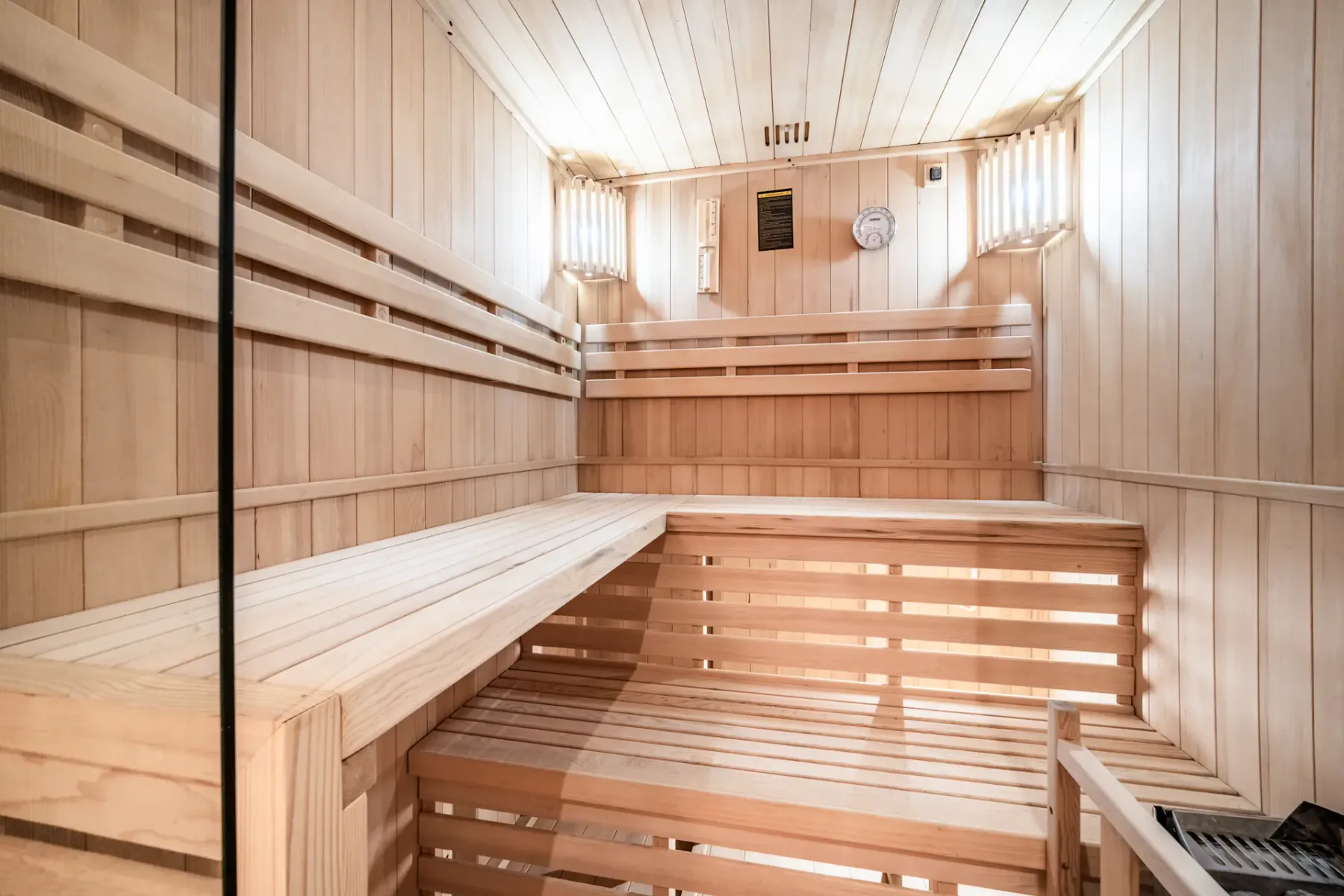 A wooden sauna room with tiered benches and a heater.