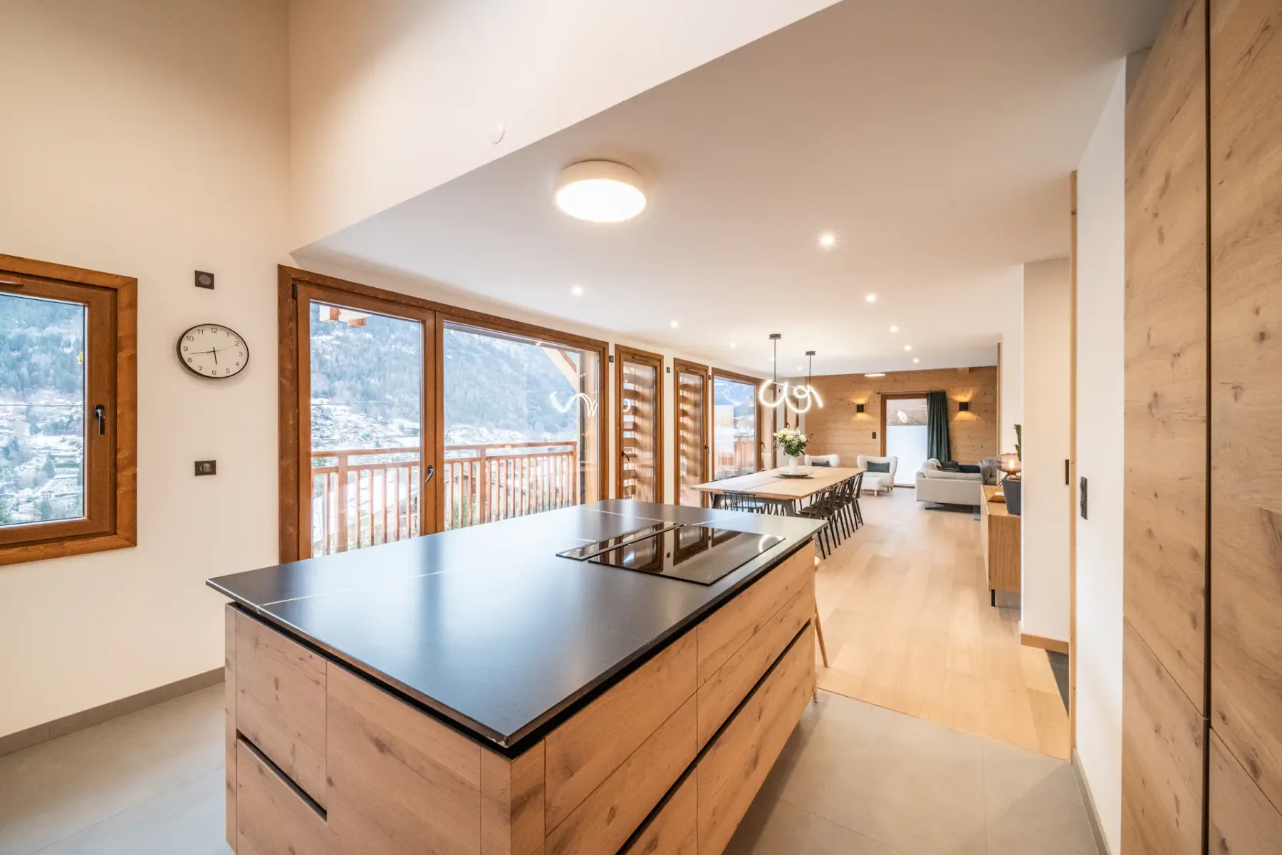 A contemporary kitchen with a large island and windows overlooking a balcony.
