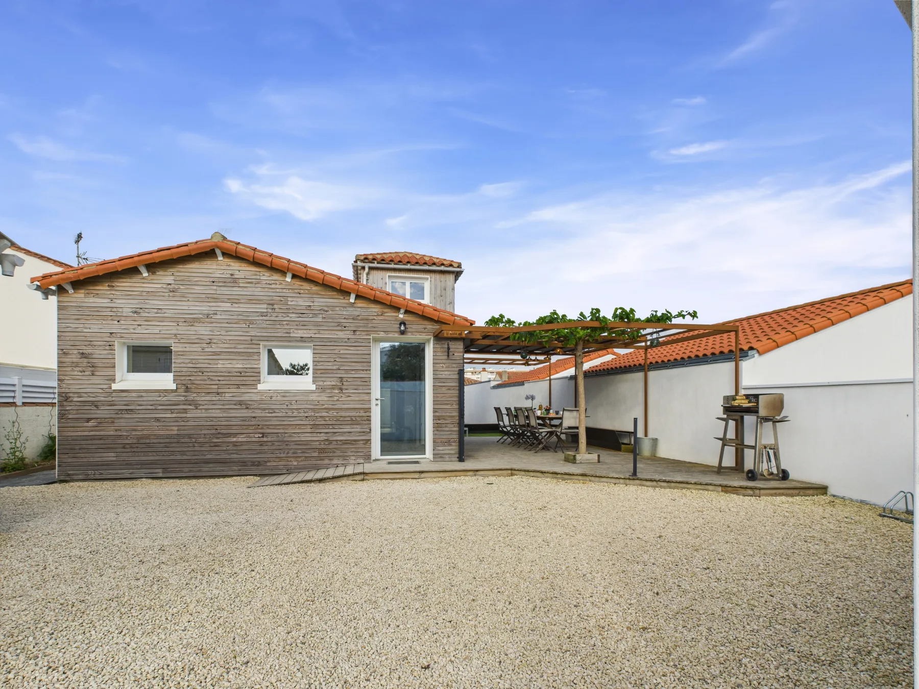 A gravel courtyard beside a wooden building, with a covered outdoor seating area.