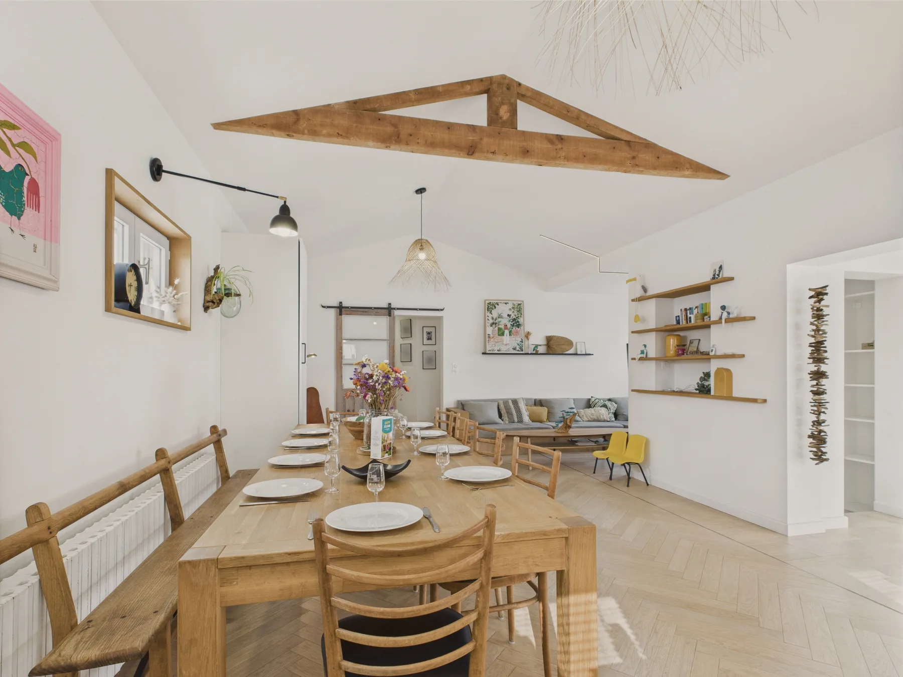 A bright dining and living area with a long wooden dining table.