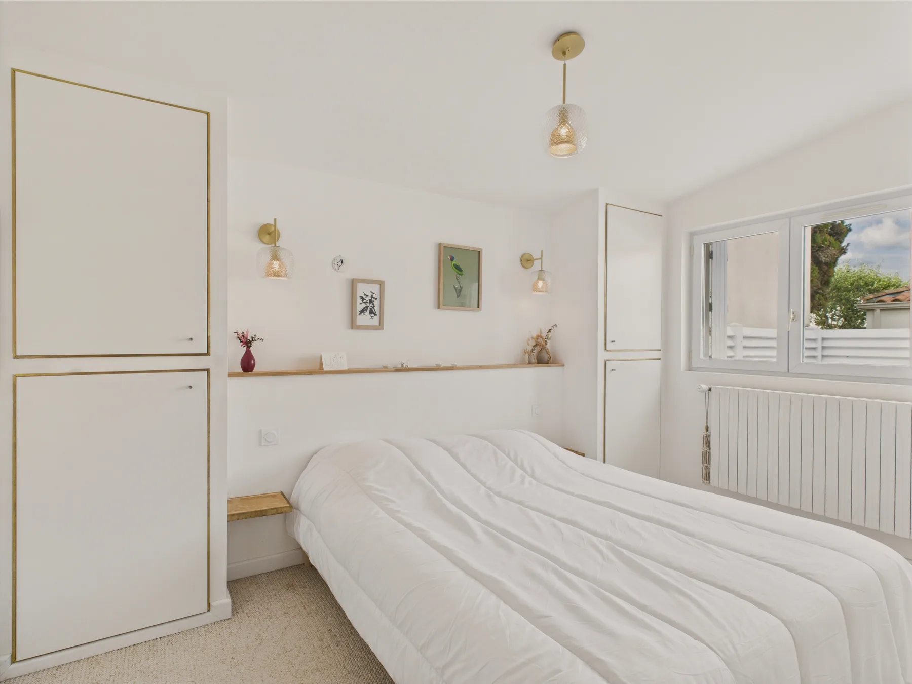 A bright bedroom with a neatly made bed and a window.