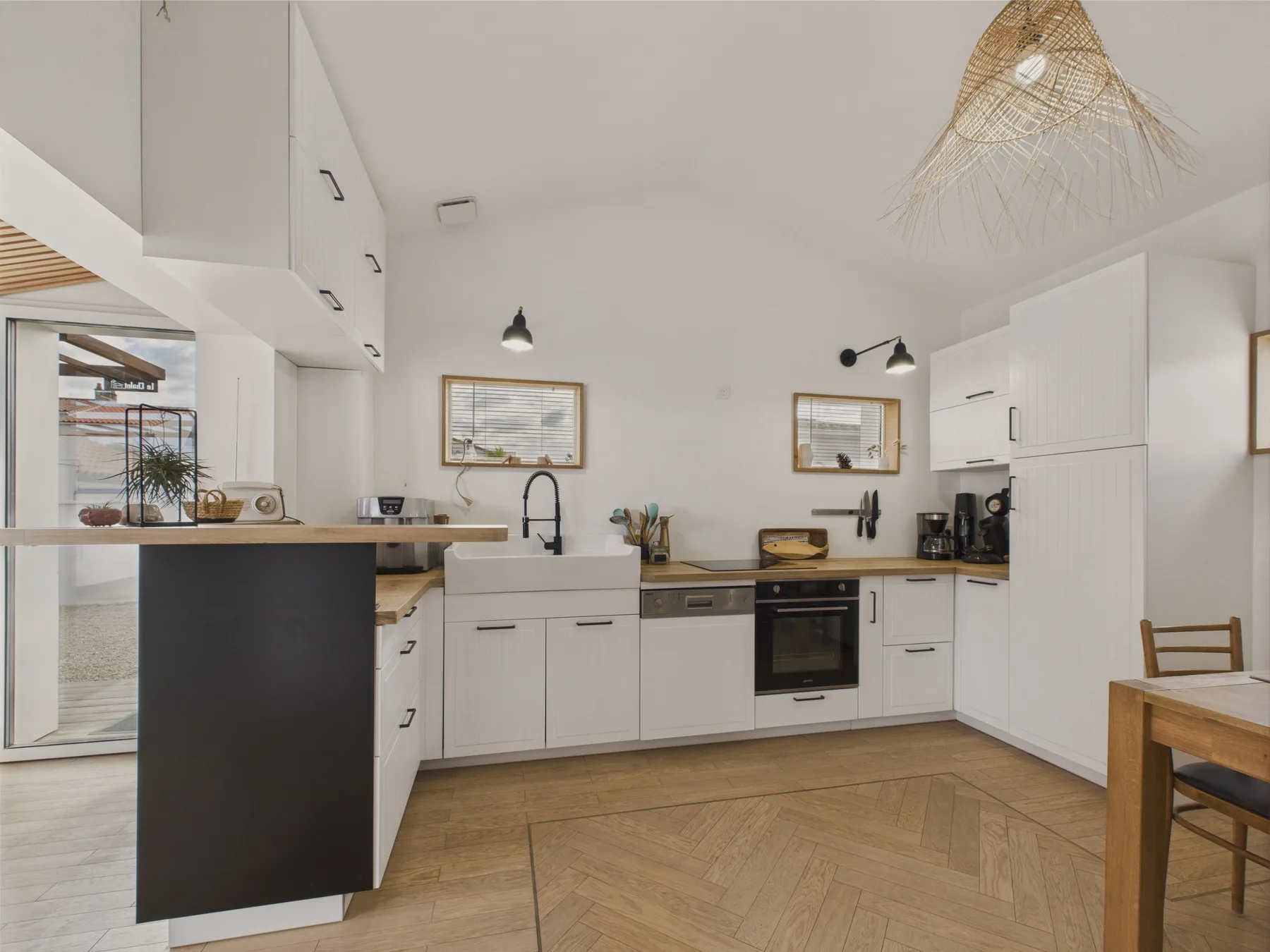 A bright kitchen with white cabinetry, a dark island, and a dining table.