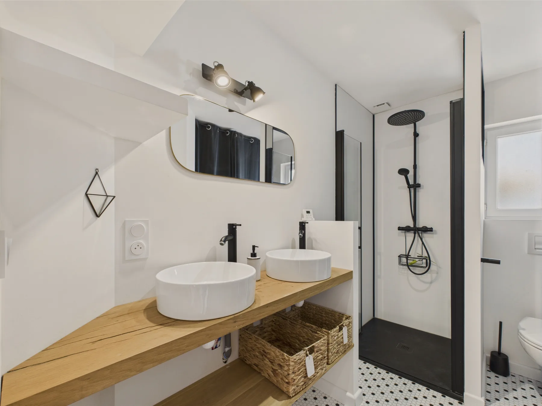 A bright bathroom with a long wooden vanity and a glass-enclosed shower.