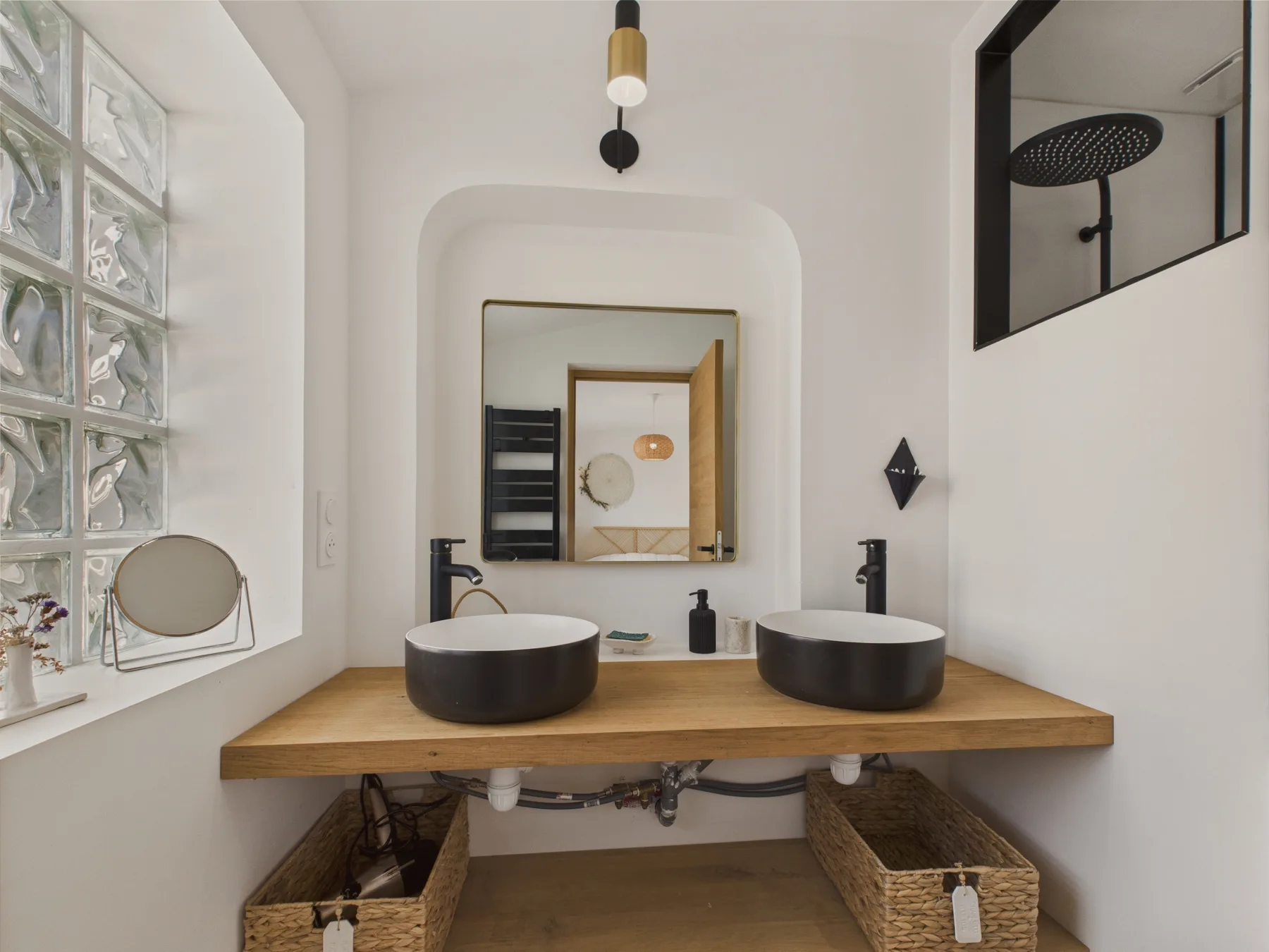 A bathroom vanity with two vessel sinks and a large mirror.