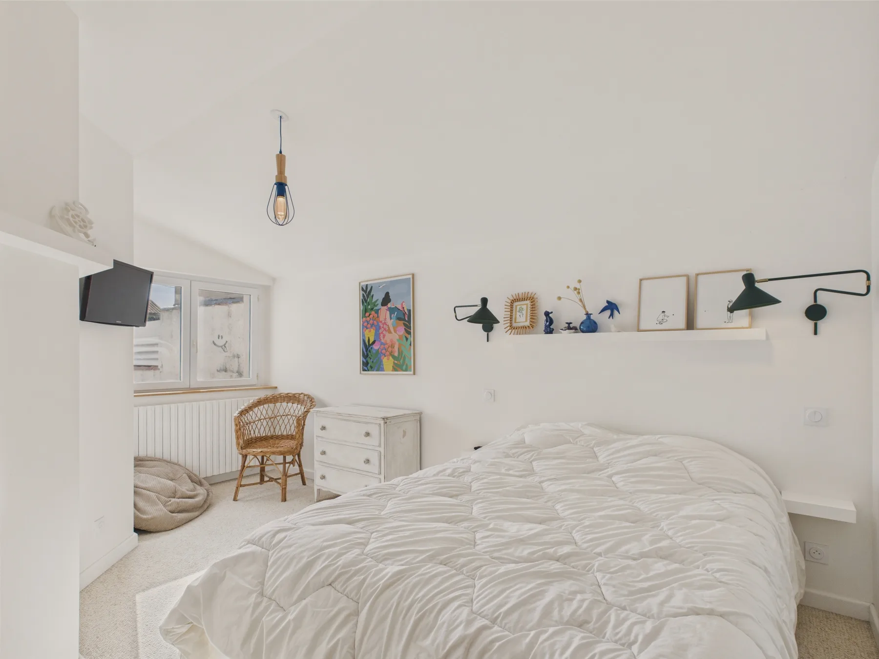 A bright bedroom with a large bed and framed artwork on the wall.