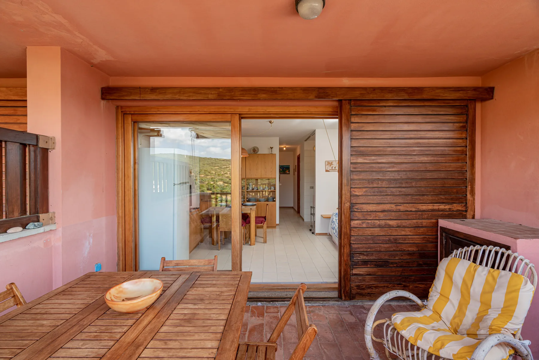 Un patio cubierto con una mesa de madera y asientos da a un comedor.