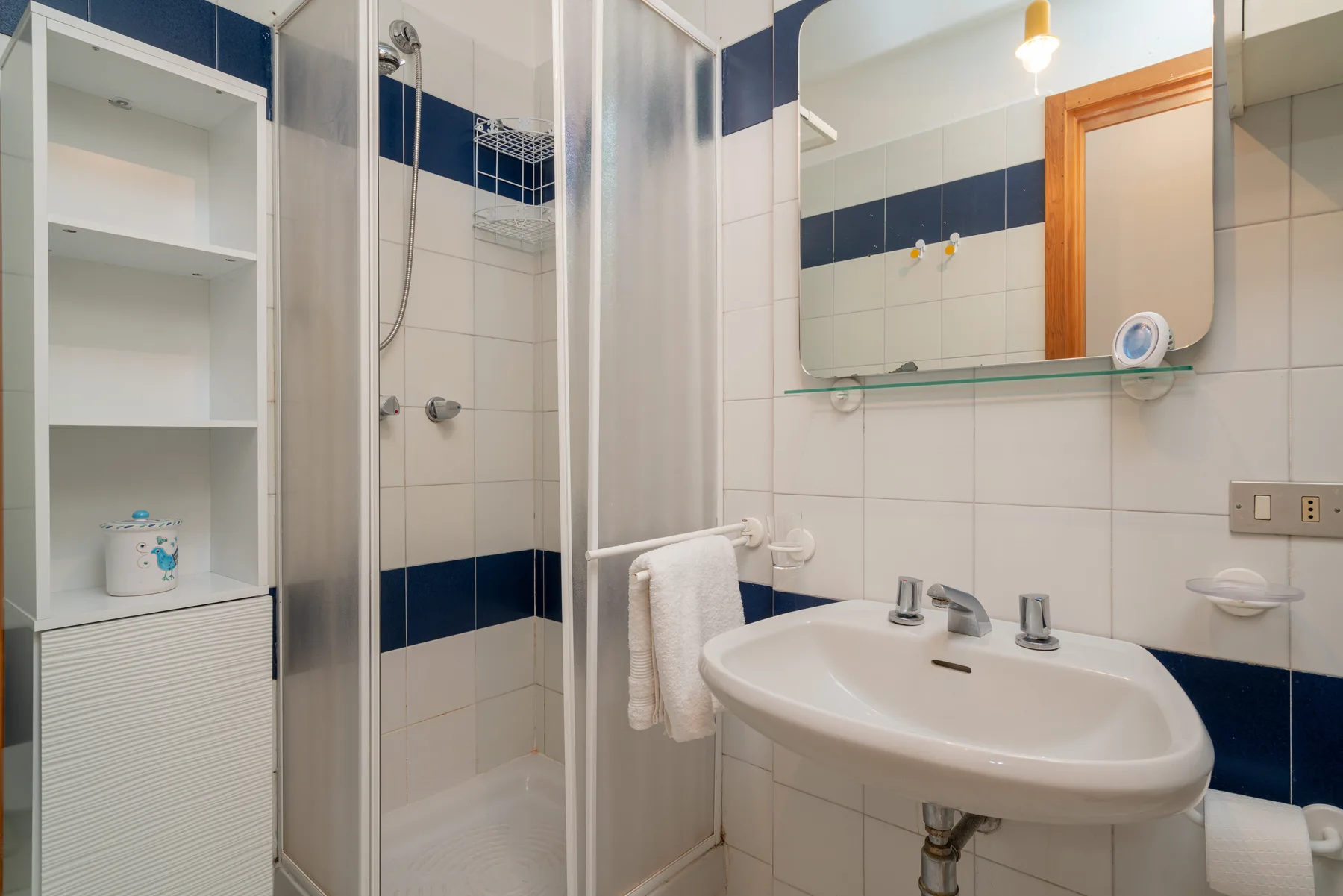 A bathroom with a sink, mirror, and shower.
