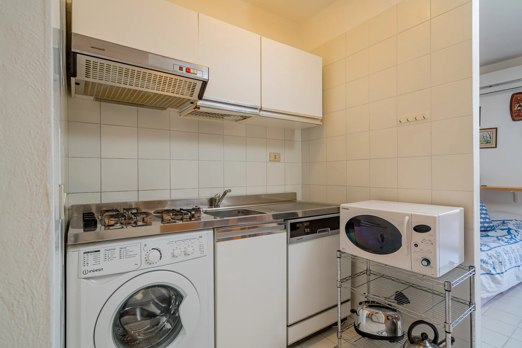A compact kitchen with white cabinets, a stovetop, and laundry appliances.