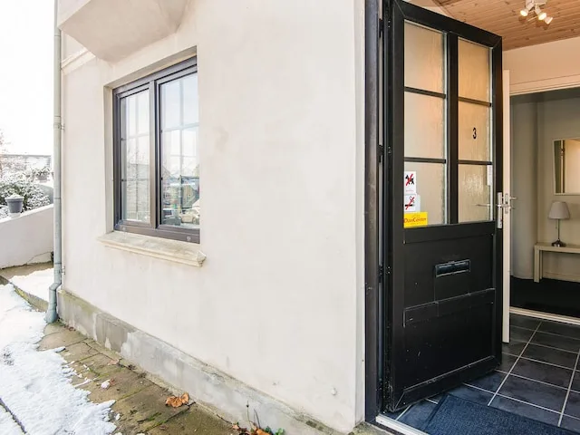 An entrance with a black-framed glass door beside a window.