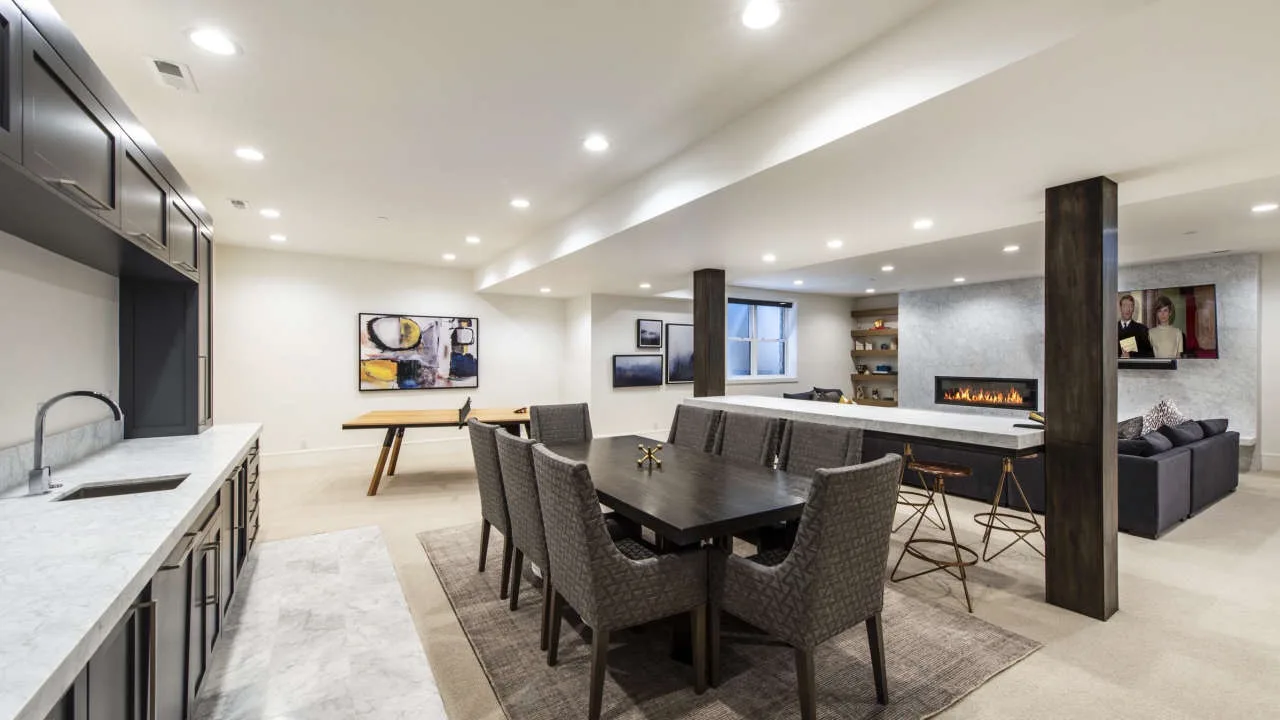 A modern open-plan kitchen and dining area with a table beside a long island.