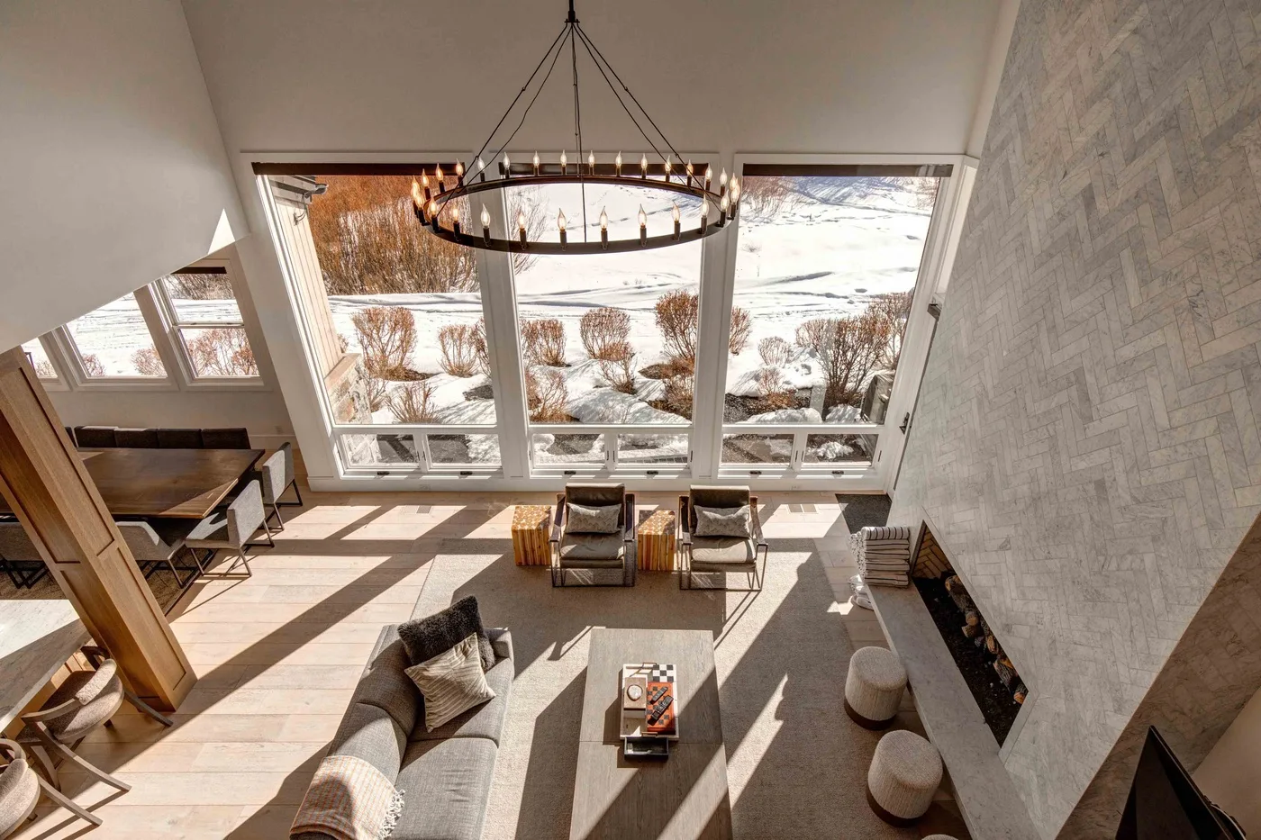 A bright living room with large windows overlooking a snowy landscape.