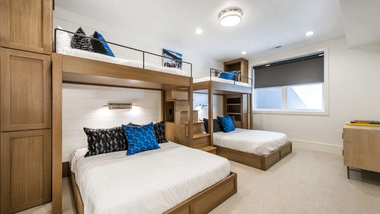 A bright bedroom with two beds and built-in wooden storage.