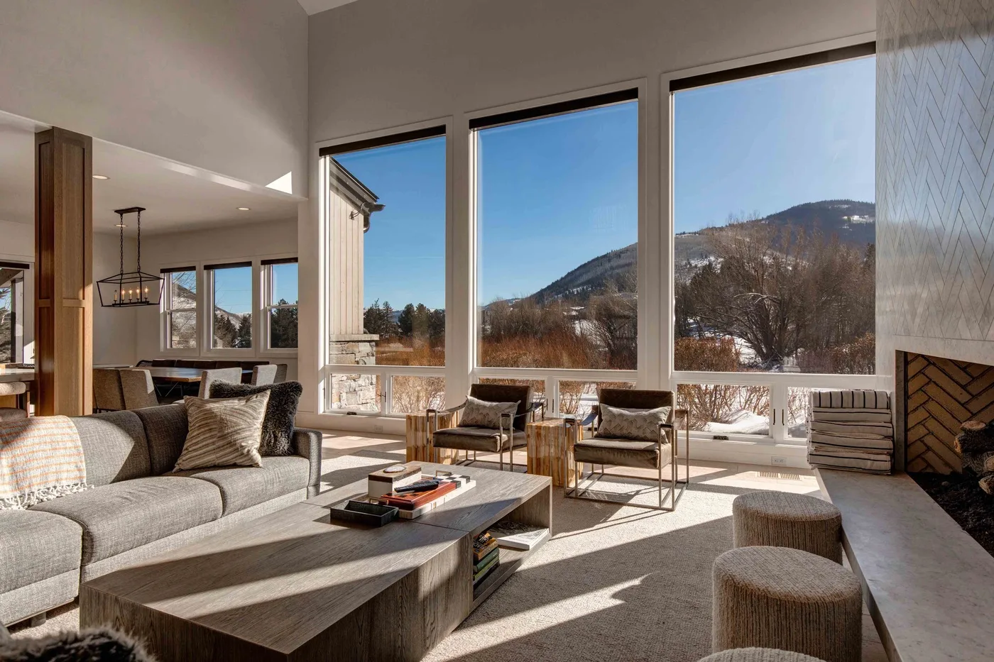 A bright living room with seating beside large windows overlooking a mountain landscape.