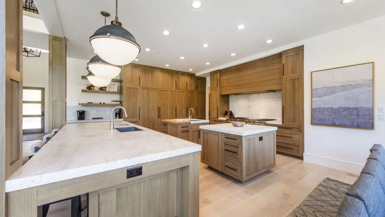 A spacious kitchen with wood cabinetry, pale countertops, and a central island.