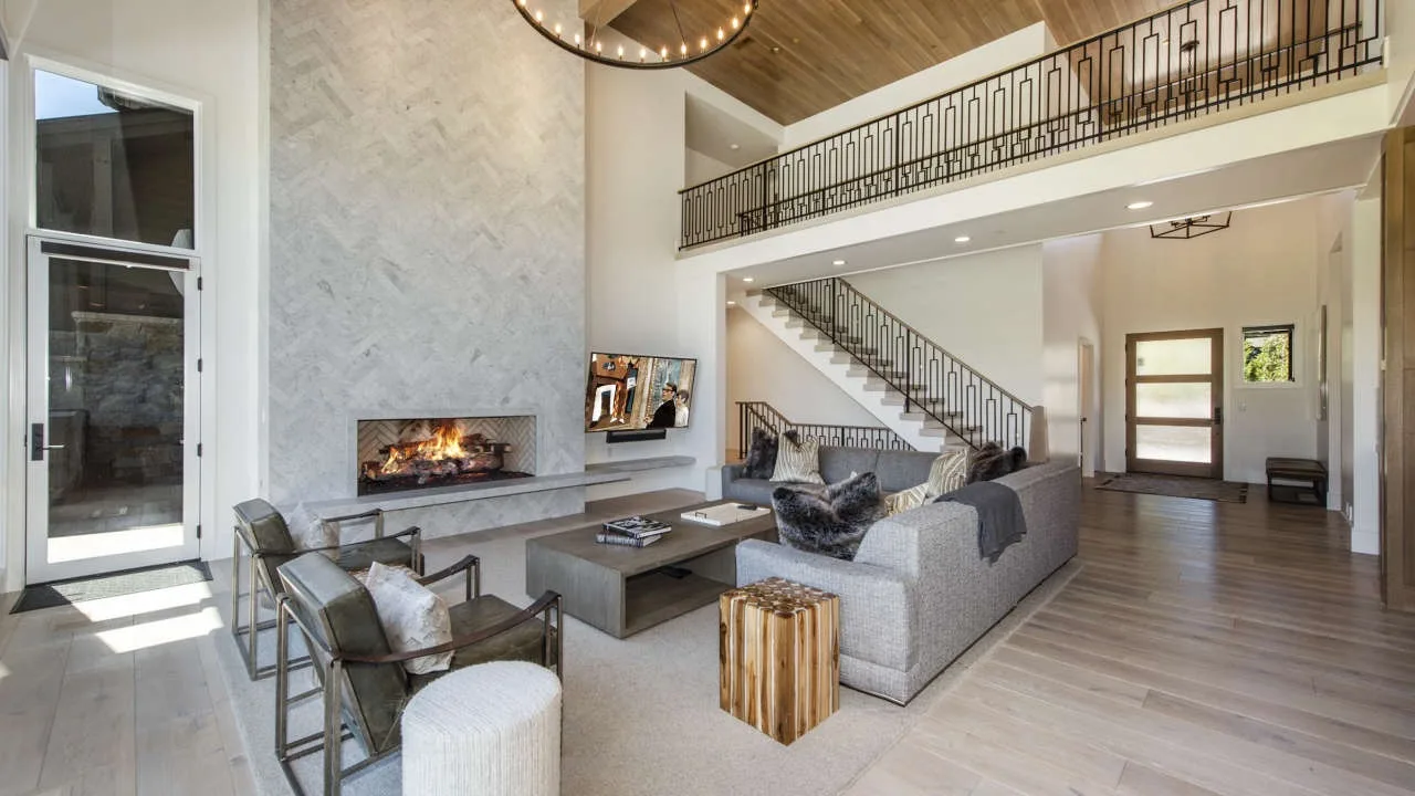 A spacious living room with a fireplace, seating, and an open staircase.