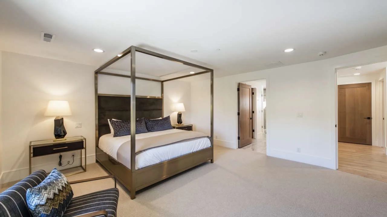 A bedroom with a four-poster bed and a small seating area.