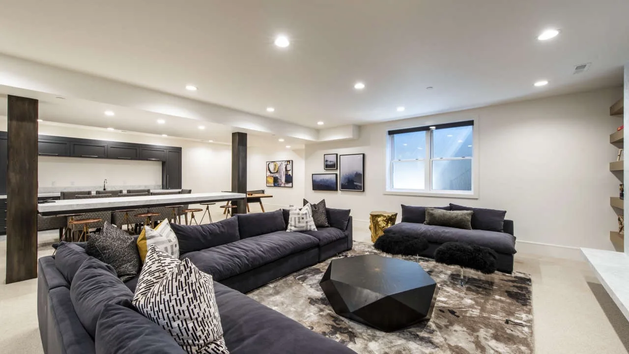 A spacious living room with dark seating around a low coffee table.
