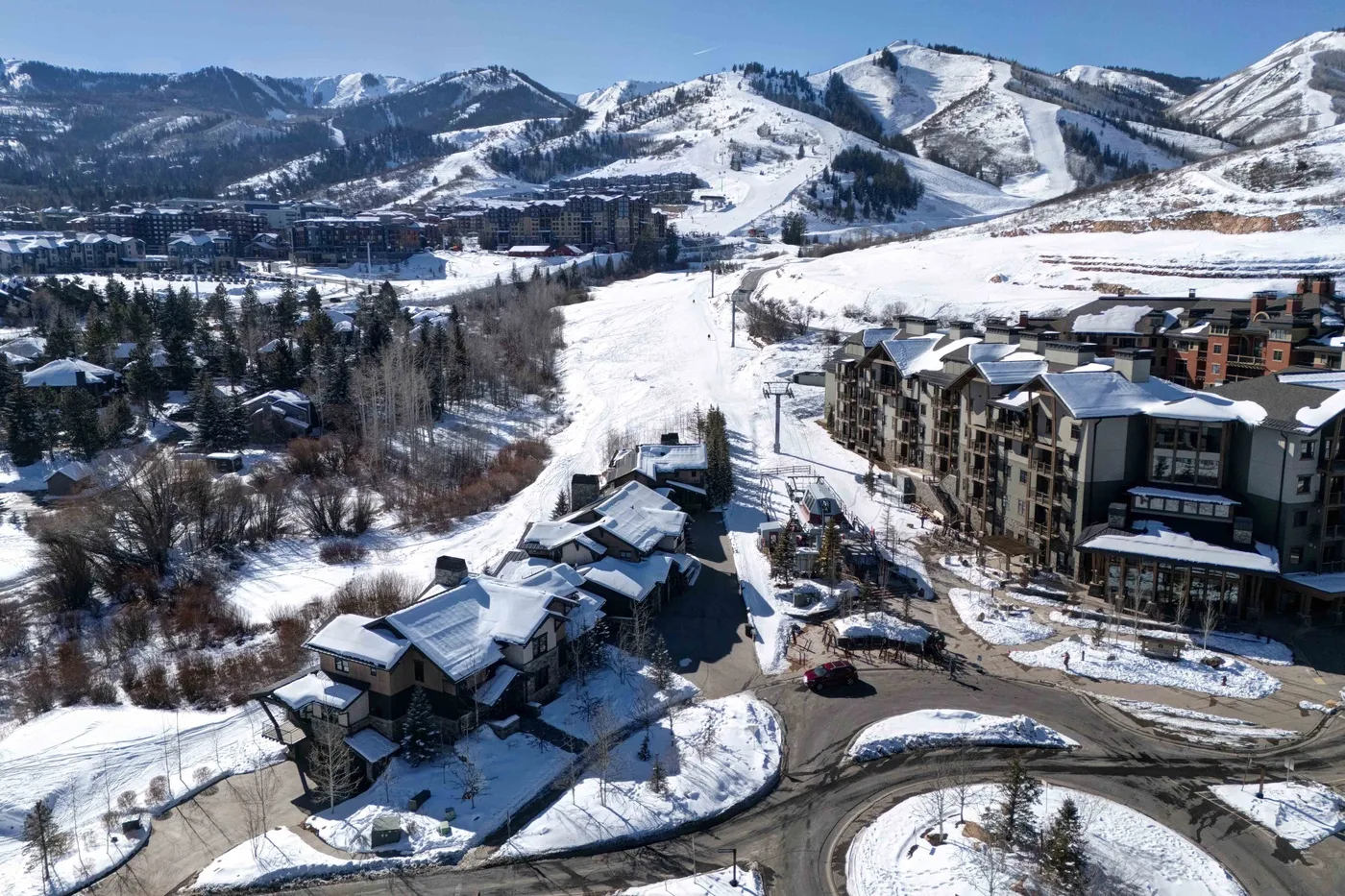 Aerial view of a snowy mountain resort with buildings beside ski slopes.