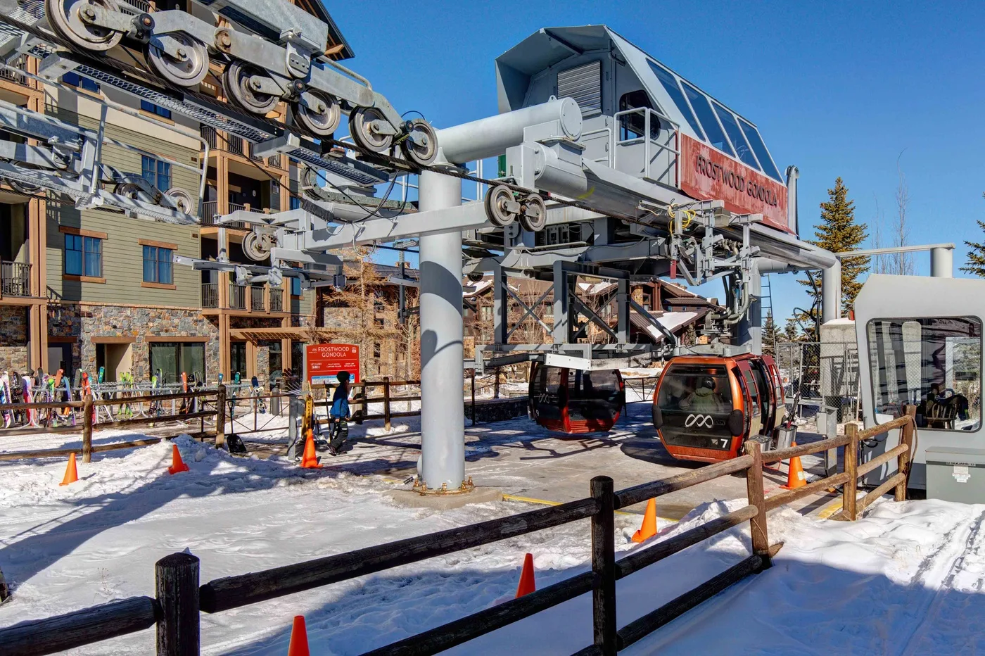 A ski gondola station with a suspended cable car above a snowy outdoor area.
