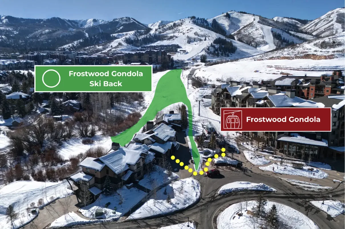 Aerial view of snow-covered buildings beside a ski slope and mountain range.