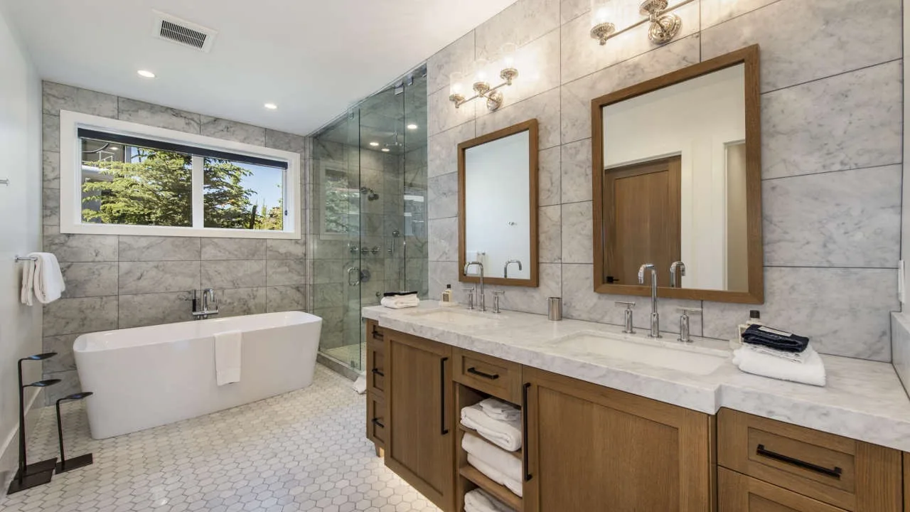 A bright bathroom with a bathtub, glass shower, and long vanity.