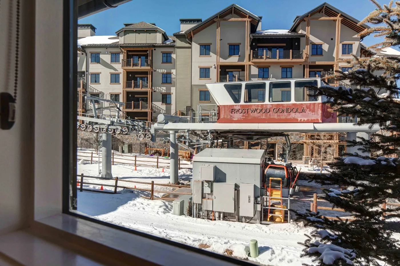 A snowy ski lift station stands in front of a multi-story building.