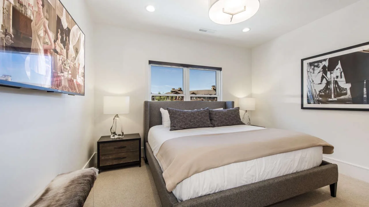 A bedroom with a neatly made bed, bedside tables, and framed artwork.