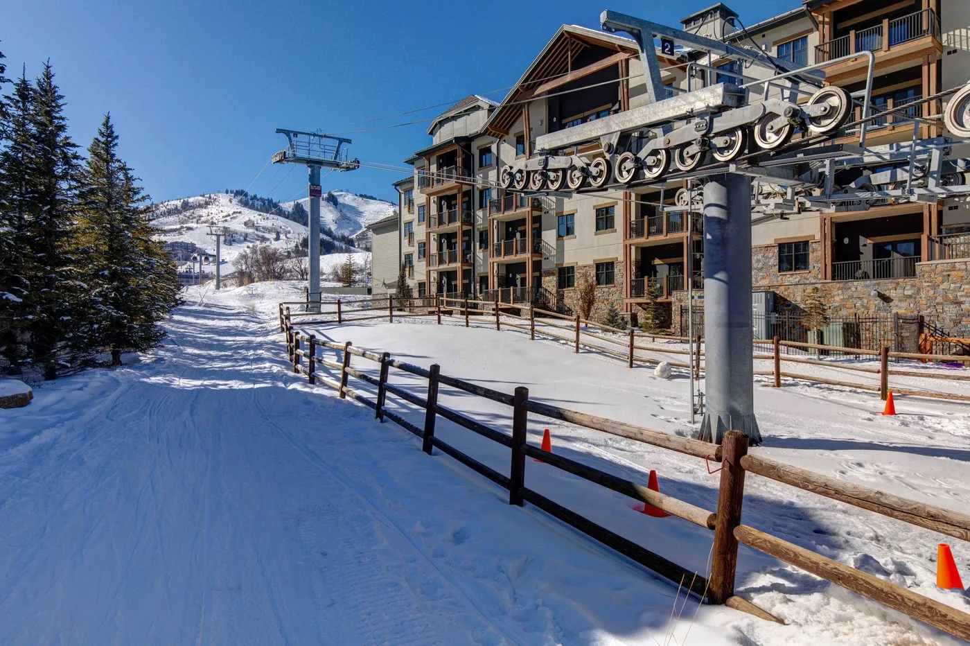A snow-covered ski slope runs beside a lodge and chairlift.