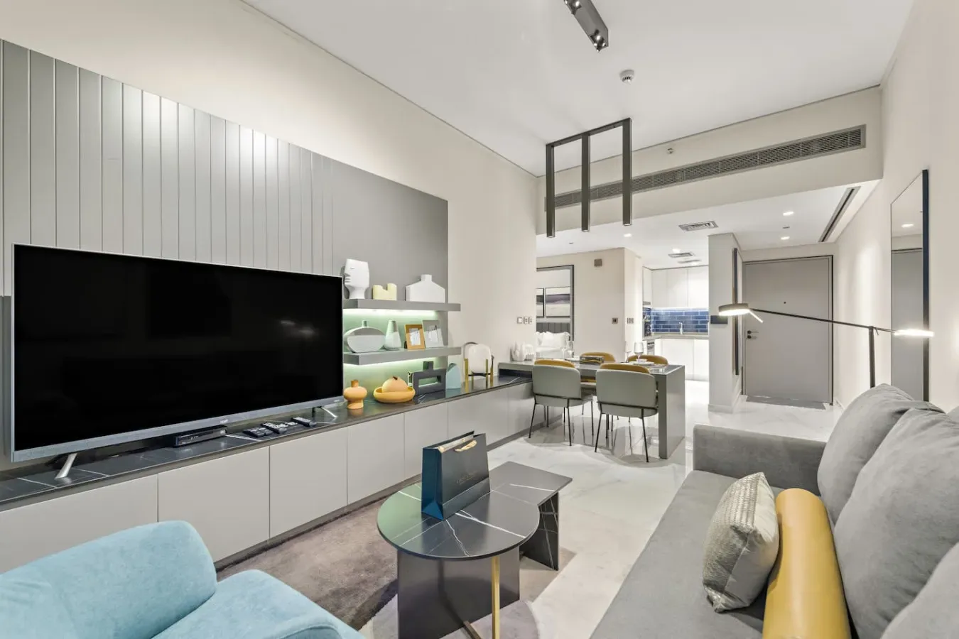 A modern living area with a television, seating, and a dining table.