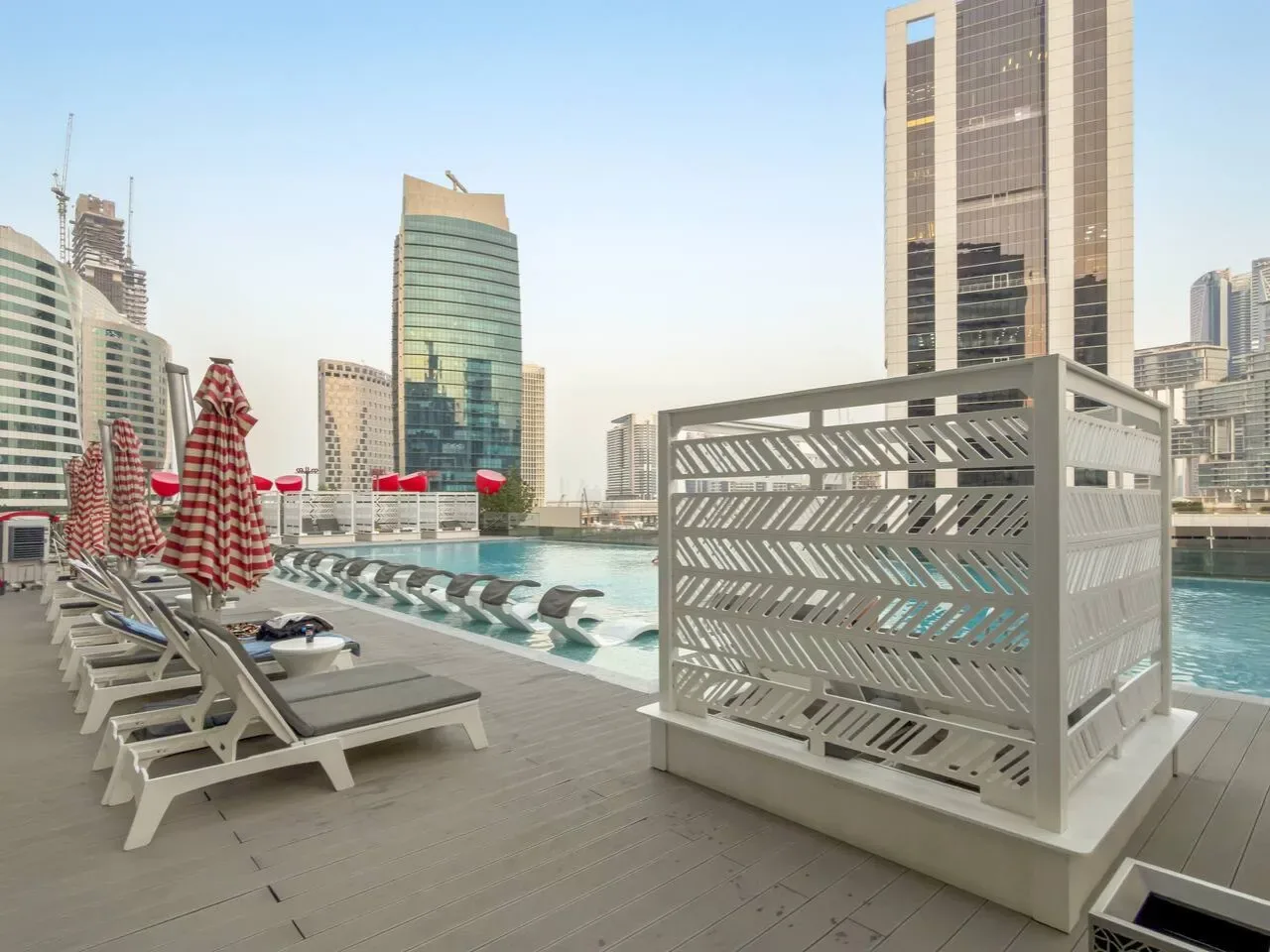 Una terraza con piscina, asientos reclinables y edificios de la ciudad al fondo.