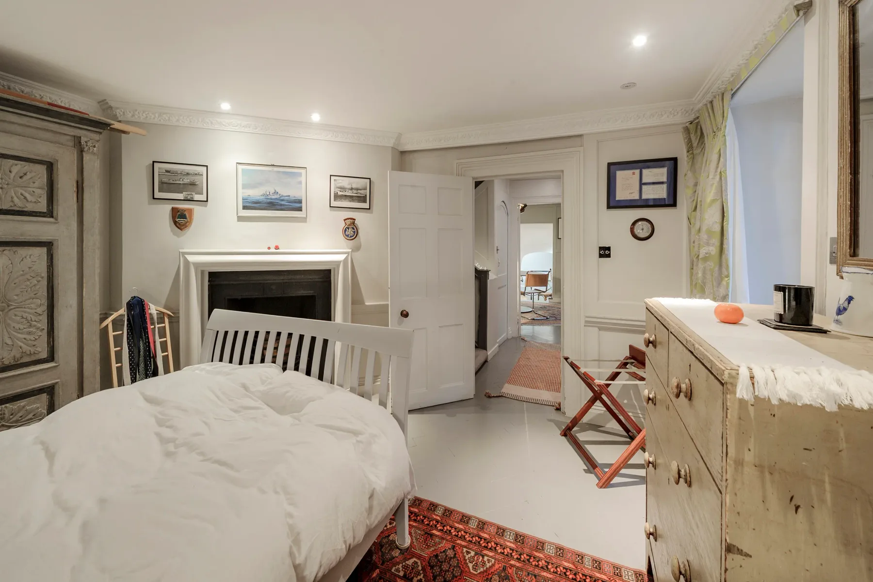 A bedroom with a bed, fireplace, and dresser.