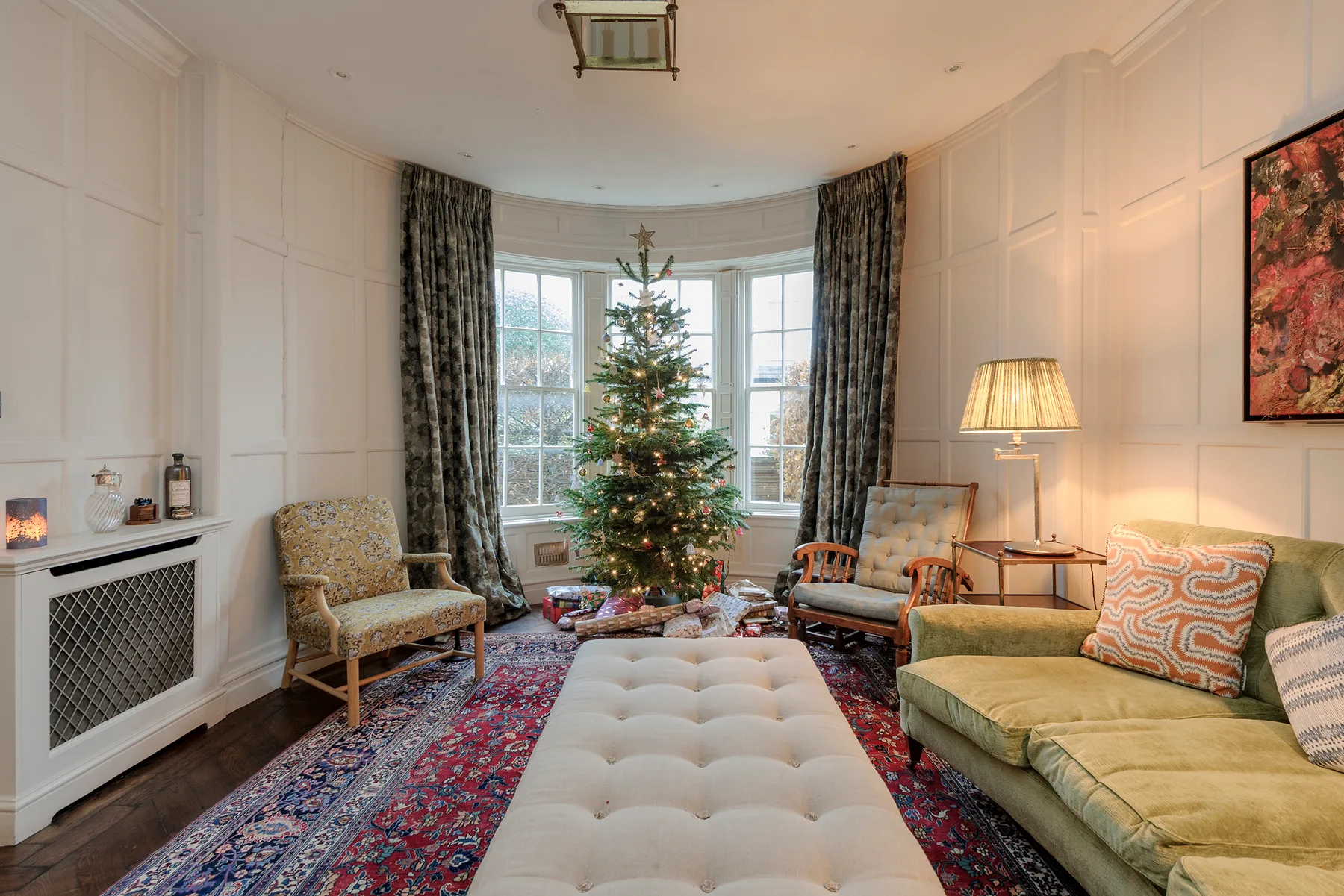 A living room with a decorated Christmas tree in front of the windows.