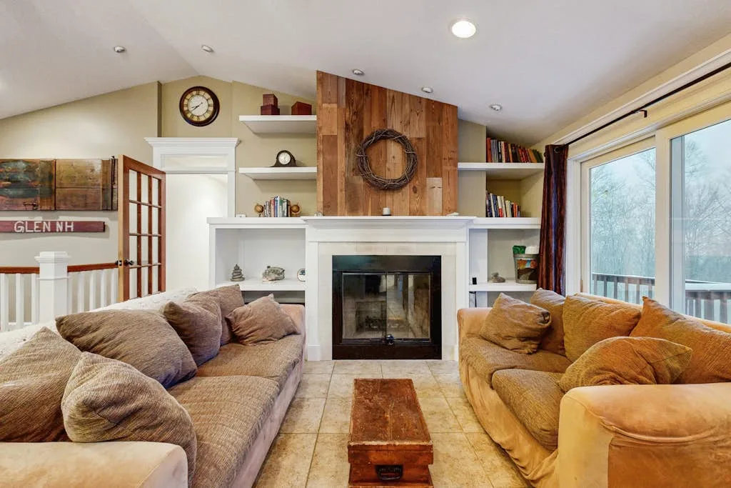 A living room with two seating areas facing a fireplace and large windows.
