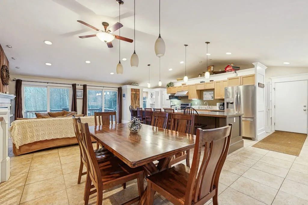 A dining area with a large wooden table beside an open kitchen.