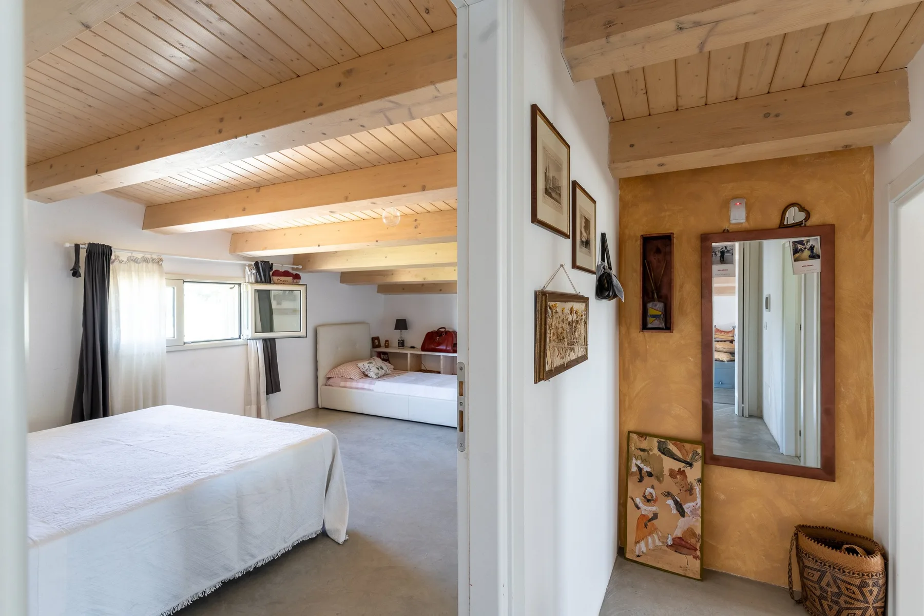Un dormitorio con una cama, una ventana y vigas de madera a la vista en el techo.