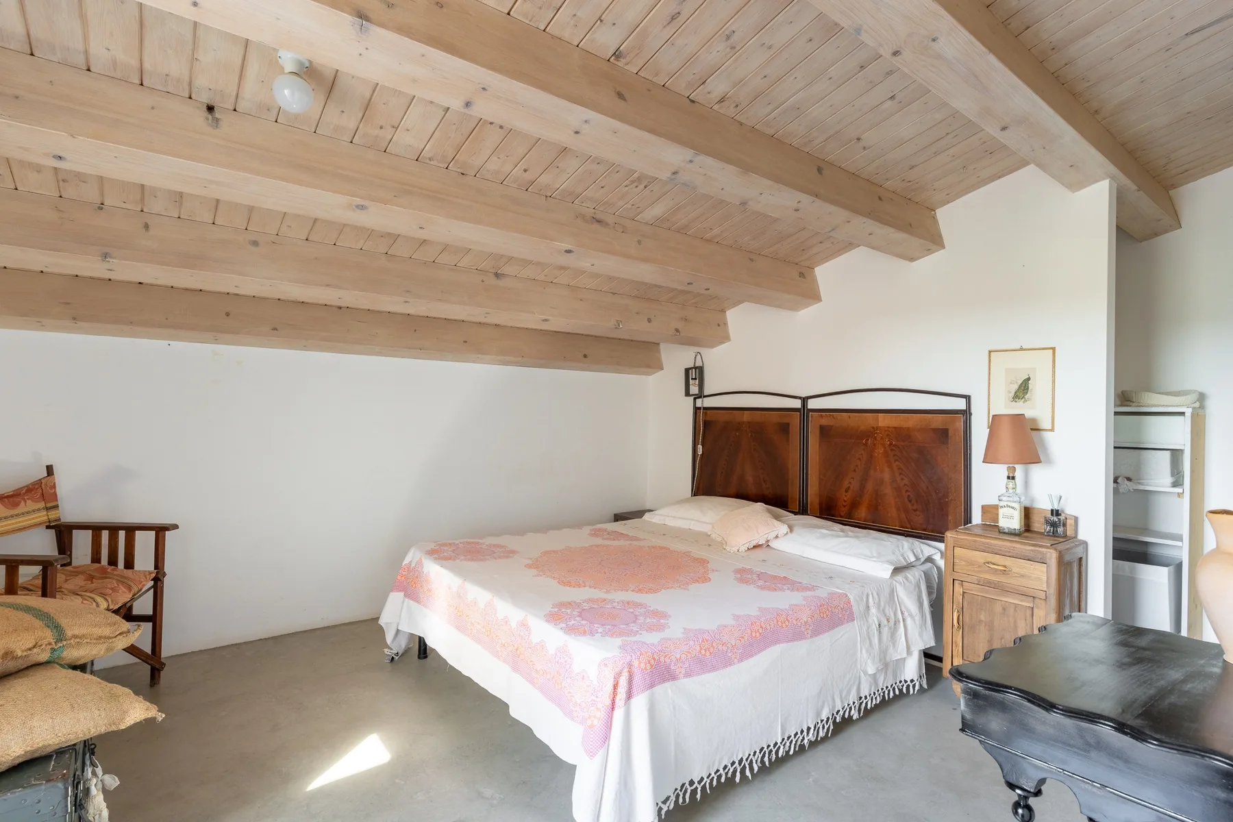 Dormitorio con una cama bajo un techo inclinado de madera.