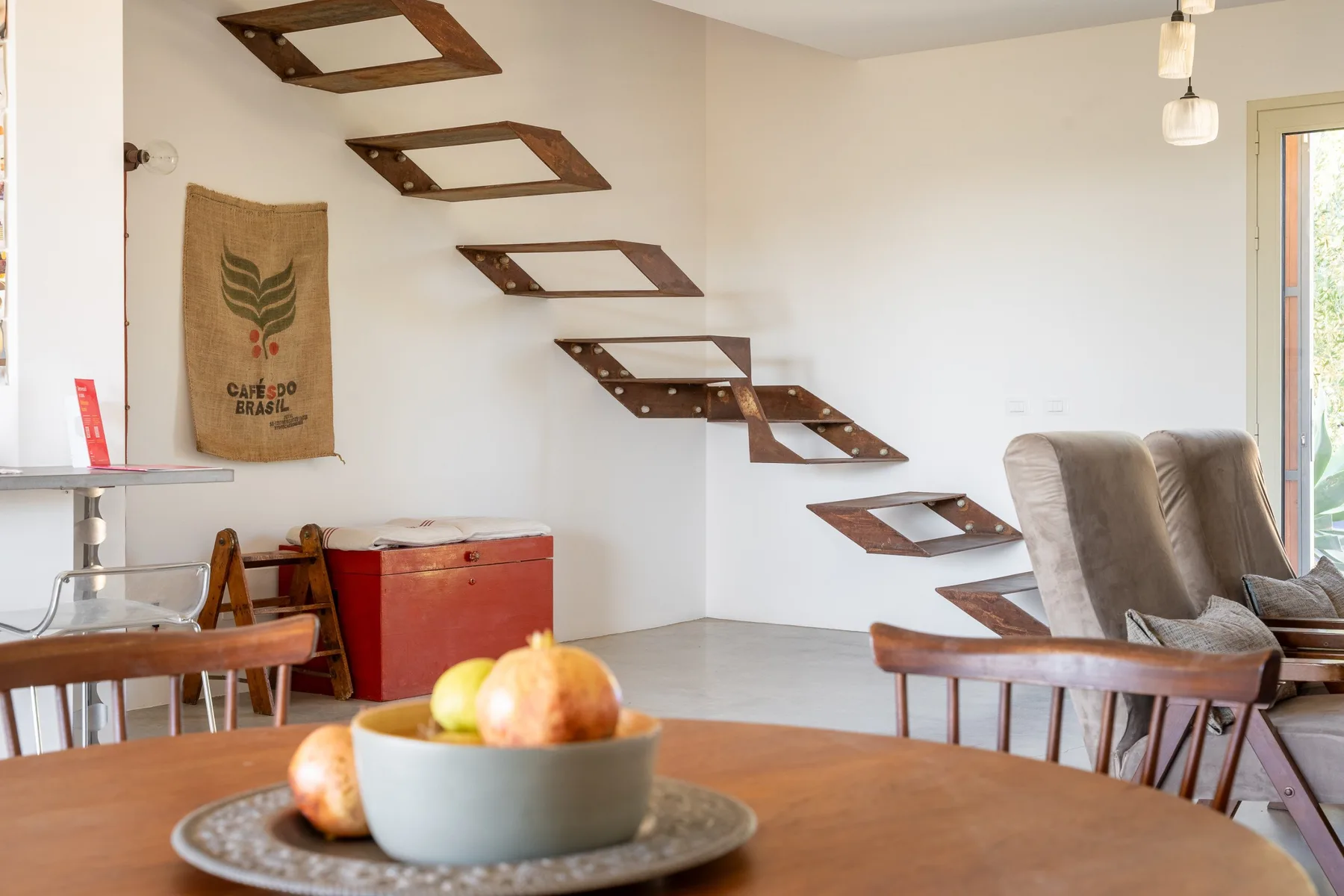 Un comedor con una mesa frente a una escalera flotante fijada a la pared.