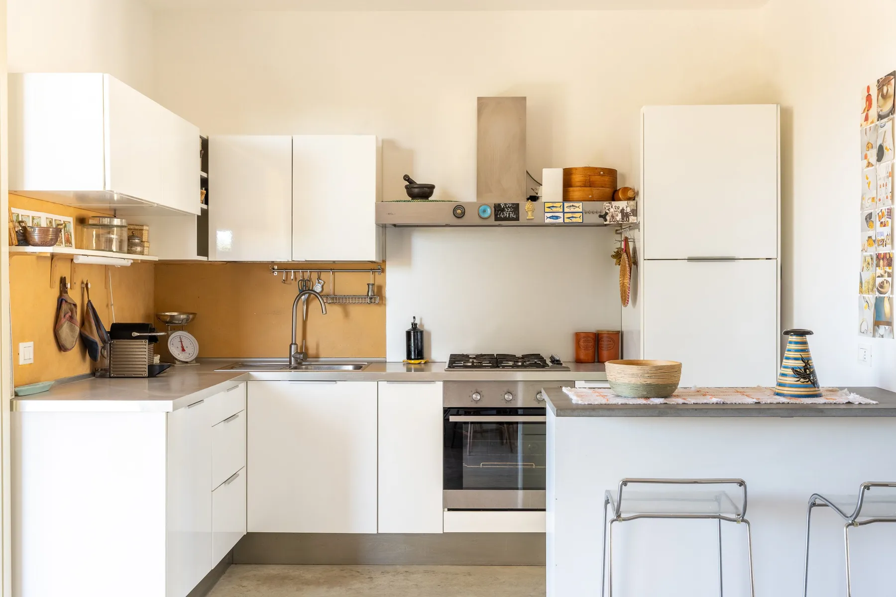 Una cocina luminosa con gabinetes blancos, una estufa y una barra con taburetes.
