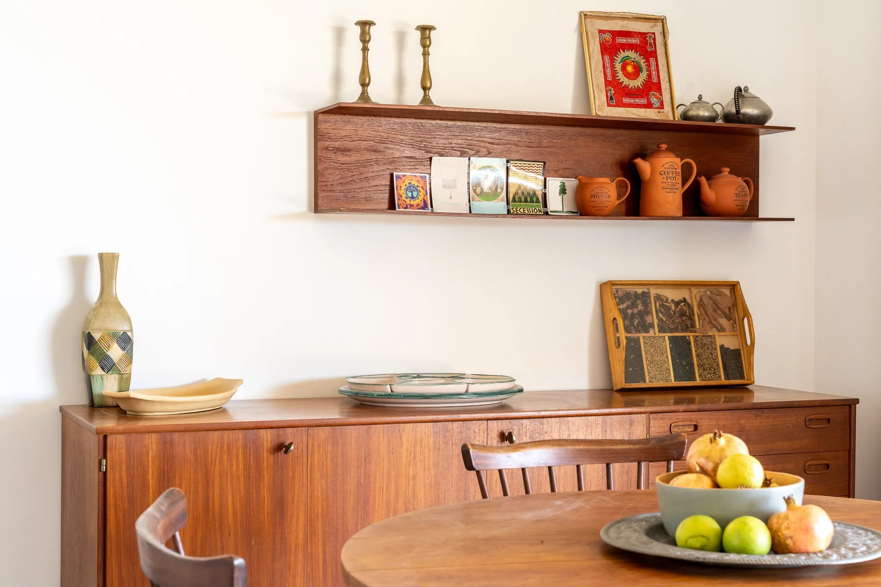Un comedor con muebles de madera, cerámica y un cuenco de fruta.