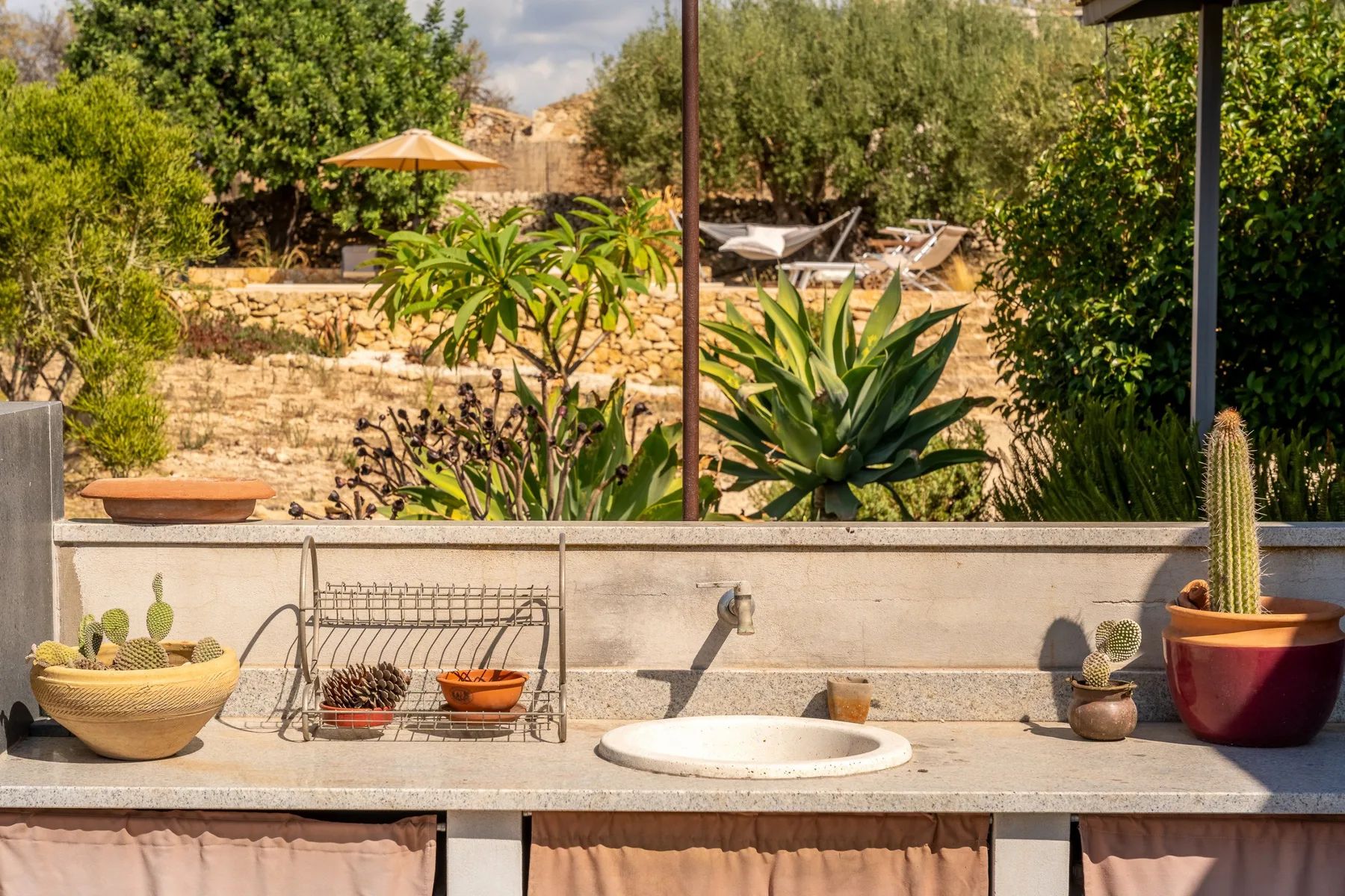Una zona exterior con lavabo de piedra da a un jardín con arbustos y suculentas.